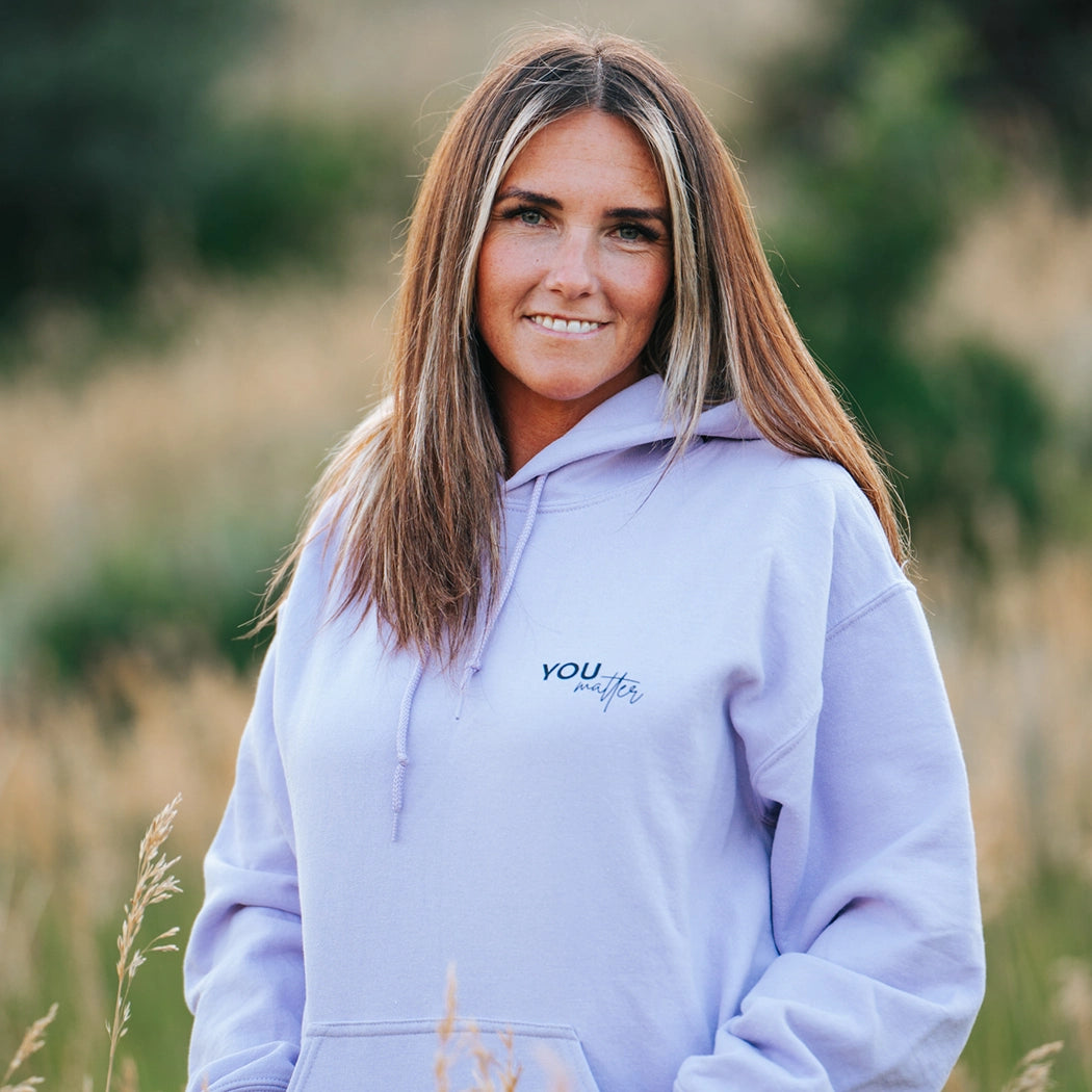 Model wearing a lavender graphic apparel hoodie that says To the person behind me: you are amazing, beautiful and enough. Remember that. The design is text only in black.