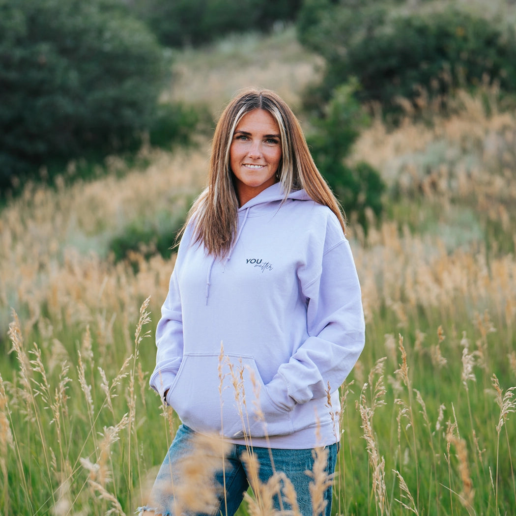 Model wearing a lavender graphic apparel hoodie that says To the person behind me: you are amazing, beautiful and enough. Remember that. The design is text only in black.