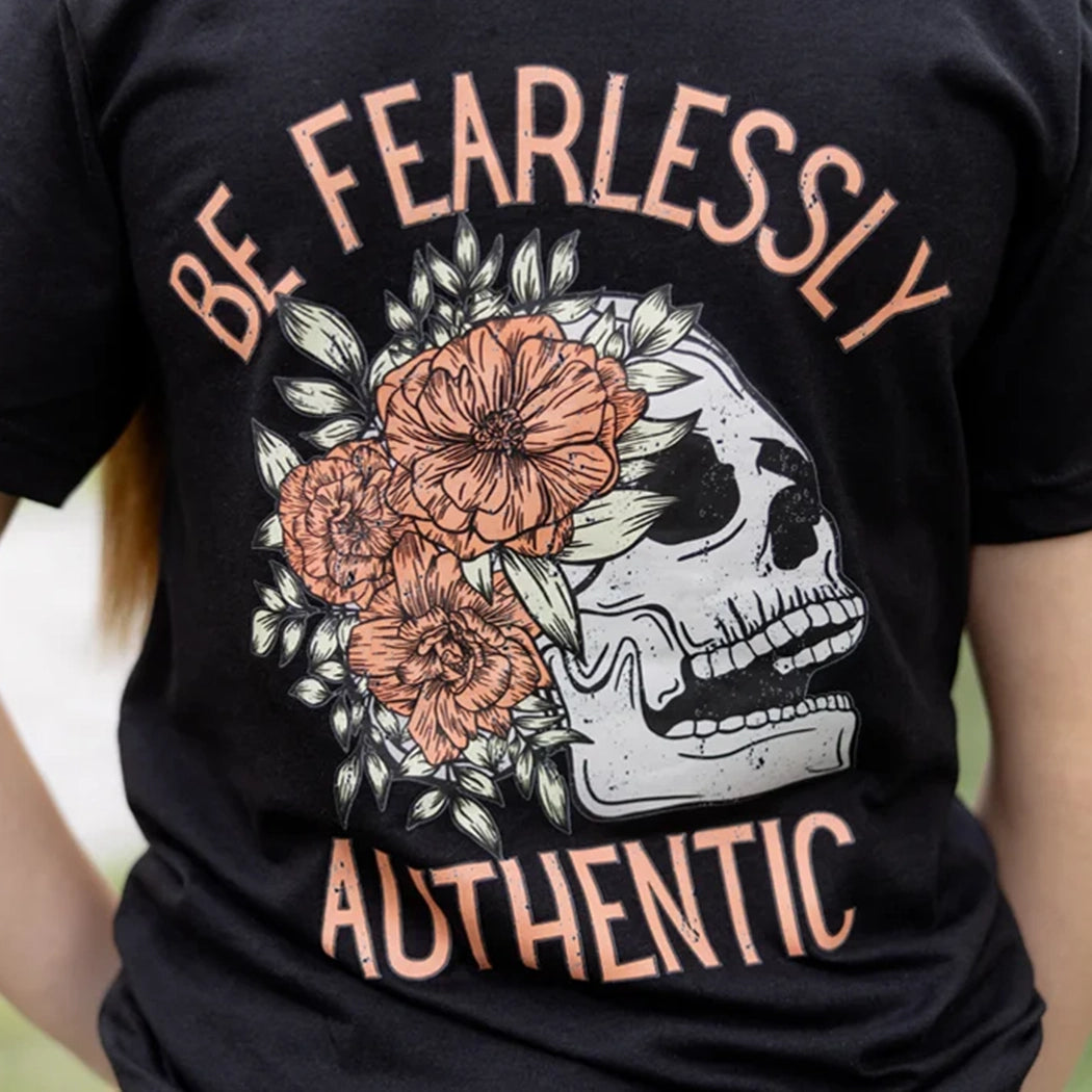 Black tshirt with light gray skeleton with flowers on front. Back of tee has gray skeleton with pink flowers in the middle and the words Be Fearlessly Authentic around it.