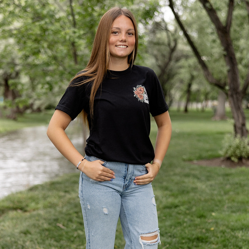 Black tshirt with light gray skeleton with flowers on front. Back of tee has gray skeleton with pink flowers in the middle and the words Be Fearlessly Authentic around it.