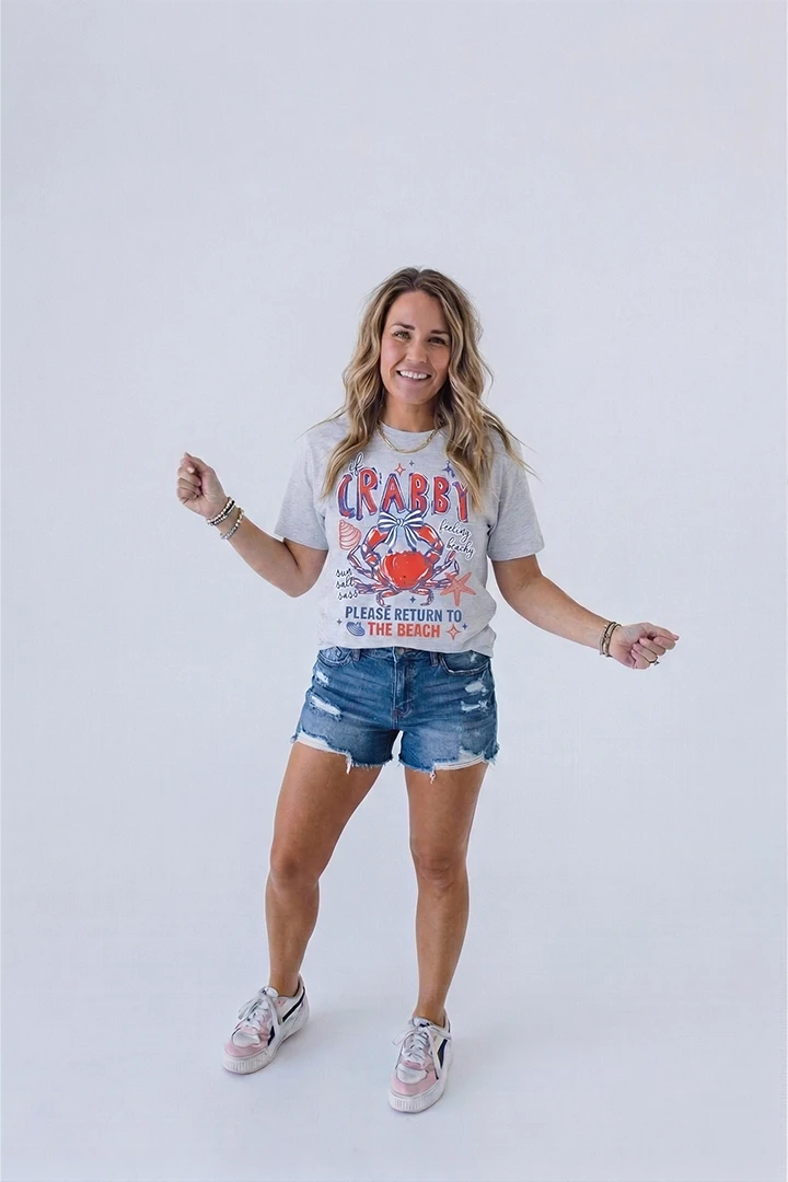 heather grey short-sleeved t-shirt. The shirt features a graphic of a red crab with a blue and white bow, a starfish, and a seashell, with text that reads 'If CRABBY feeling beachy' and 'PLEASE RETURN TO THE BEACH'.