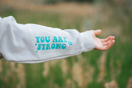 Sleeve of hoodie that says you are strong with flowers. 