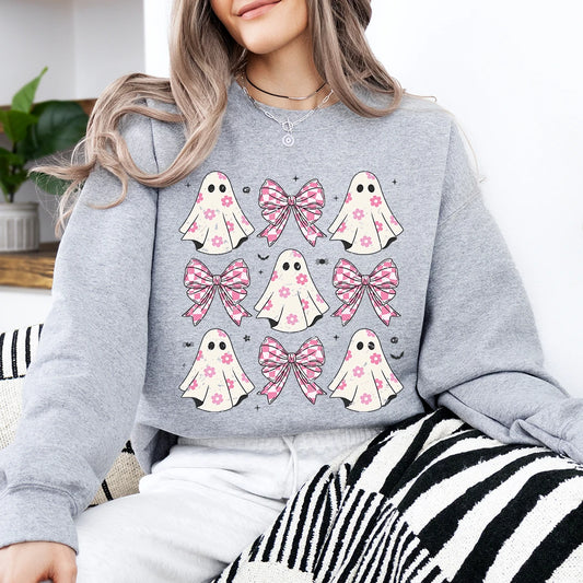 Person wearing a gray sweatshirt with pink ghost and bow designs.