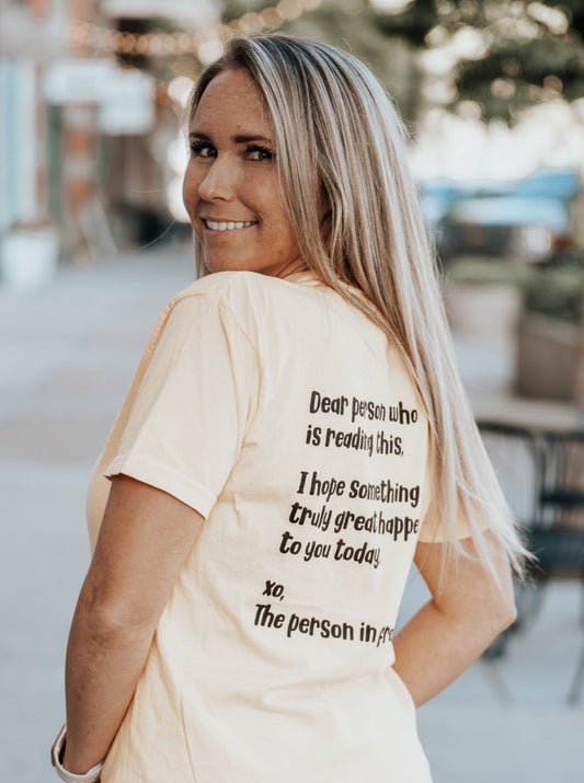 Dear person who is reading this, I hope something truly great happens to you today. xo, the person in front of you. Yellow t-shirt with black text. Back of shirt.