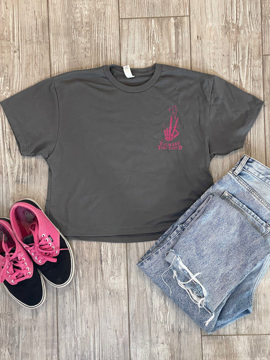 Gray crop top with pink design that says Talking Too Loud. Peace skeleton fingers with lighting bolt and sparkles. Jeans and vans black and pink shoes. Flat lay. 