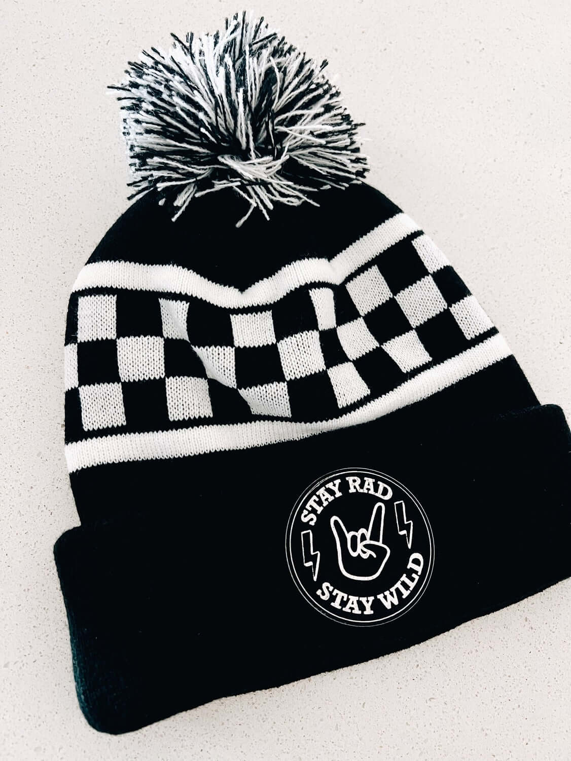 Black and white with checkered beanie. Patch that has rocker fingers and lightning bulb that says stay rad and wild.