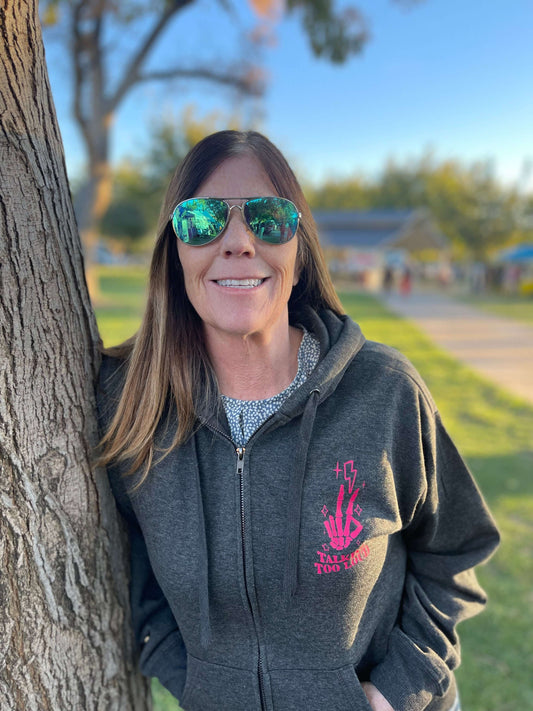 Gray zip up with pink design that says Talking Too Loud. Peace skeleton fingers with lighting bolt and sparkles. 