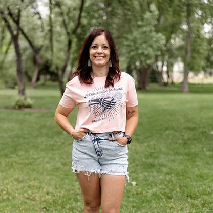 Pink crop top shirt with positive message that says Let Your Voice Be Heard. The design has a Skelton hand with a microphone.  