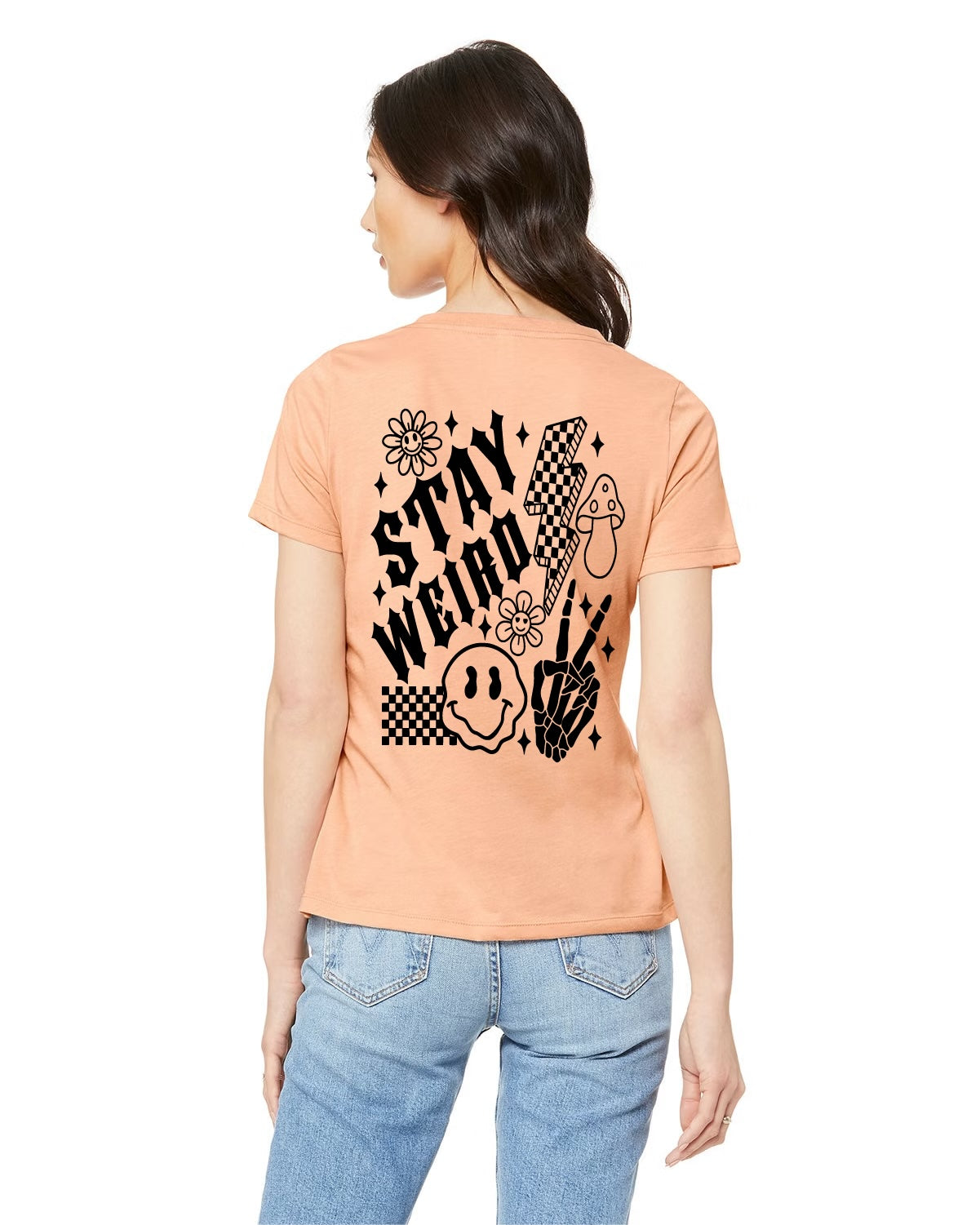 Peach shirt with black design. Checkered design with droopy smile face, lightning bulb, mushroom, flowers and skeleton fingers. Shirt says stay weird. 