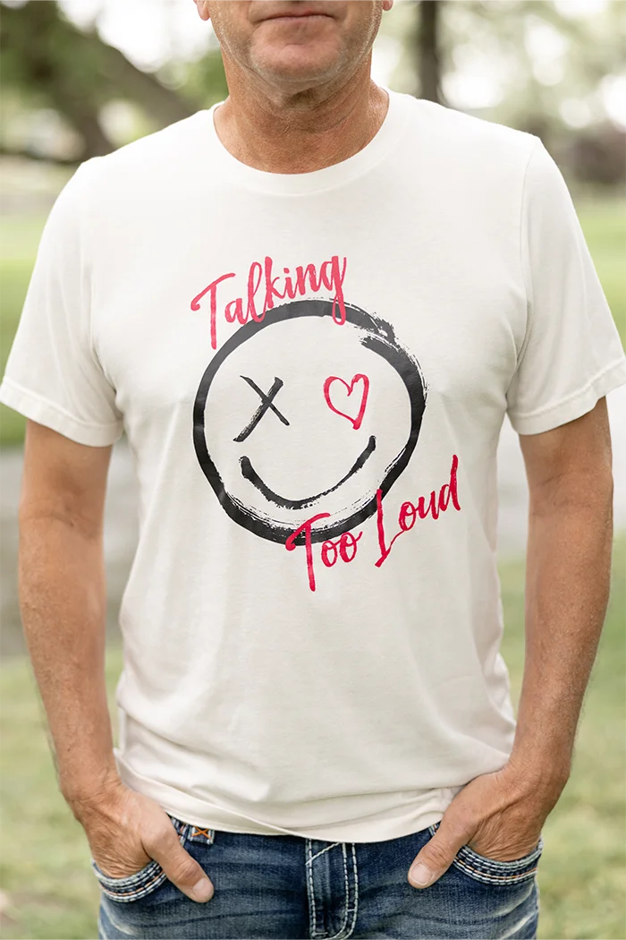 Tan shirt with the Talking Too Loud logo.