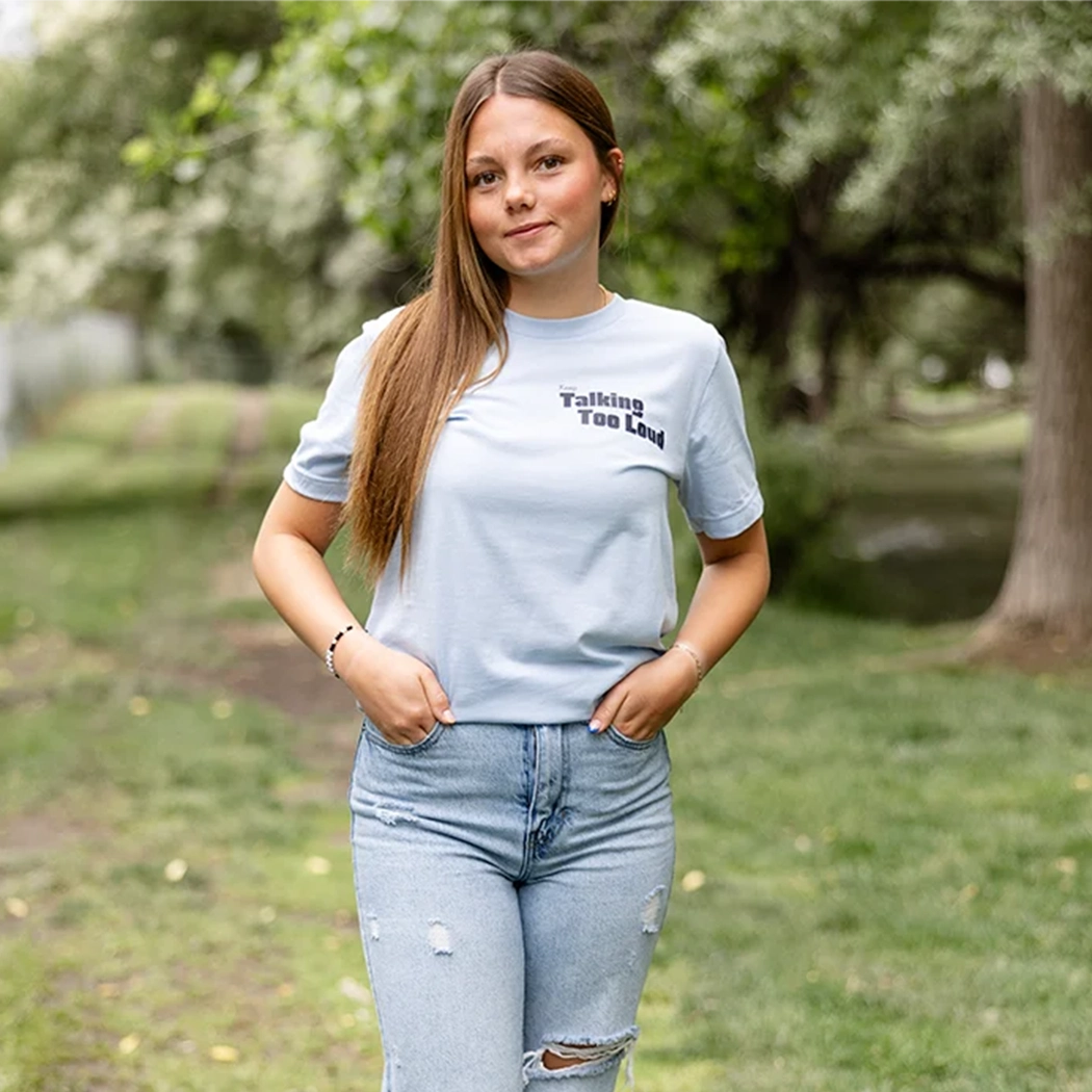 Woman wearing  blue graphic tee with saying "Ways to keep Talking Too Loud"