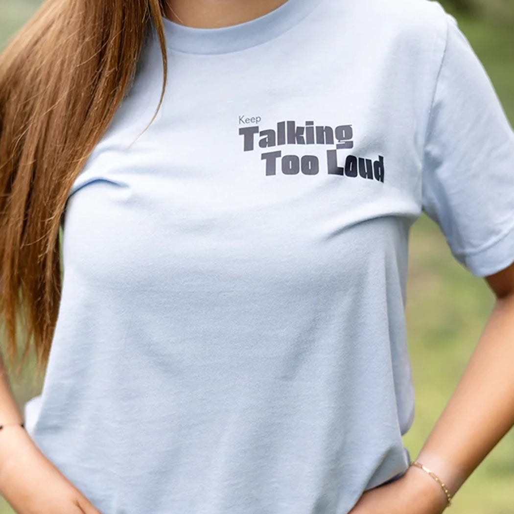 Woman wearing  blue graphic tee with saying "Ways to keep Talking Too Loud"