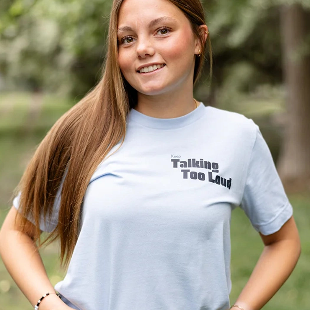 Woman wearing  blue graphic tee with saying "Ways to keep Talking Too Loud"