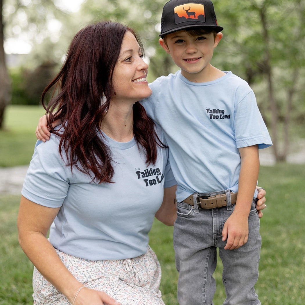 Woman and kid wearing  blue graphic tee with saying "Ways to keep Talking Too Loud"