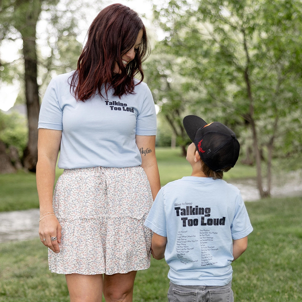 Woman and kid wearing  blue graphic tee with saying "Ways to keep Talking Too Loud"