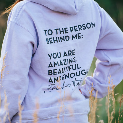 Model wearing a lavender graphic apparel hoodie that says To the person behind me: you are amazing, beautiful and enough. Remember that. The design is text only in black.