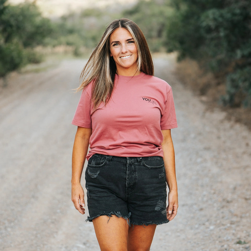 Model wearing mauve shirt that says To the person behind me: you are amazing, beautiful and enough. Remember that. The design is text only in black.